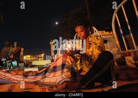 Un manifestante illumina una partita durante le proteste contro la brutalità della polizia, contrassegnata come EndSARS a Lagos Nigeria il 10 ottobre 2020. Foto Stock