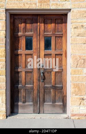 Vecchio marrone rossastro antico doppia porta d'ingresso su un beige muro di pietra in piena luce del sole Foto Stock