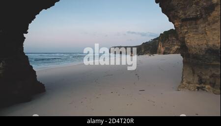 Punto di riferimento turistico dell'Indonesia: Gigantesco buco di parete rocciosa sulla spiaggia di sabbia di Bawana, Isola di Sumba. Formazione geologica rocciosa unica all'aerea della baia dell'oceano. Batu Bolong - attrazione naturale del paradiso tropicale Foto Stock