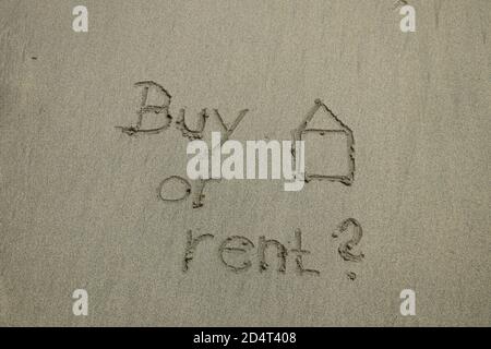 acquistare o affittare concetto, testo sulla sabbia, immobiliare. Il segno scritto sulla sabbia Foto Stock
