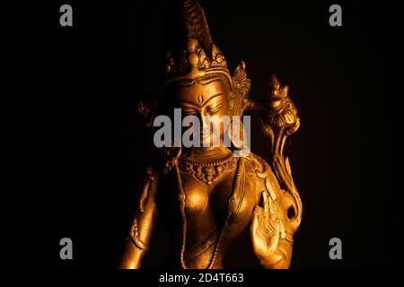 Primo piano di isolato illuminato hindu Shiva dio bronzo dorato statua con mano rialzata su sfondo nero vuoto Foto Stock