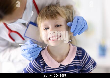 Dentista medico esamina i denti di piccola ragazza sorridente in clinica Foto Stock