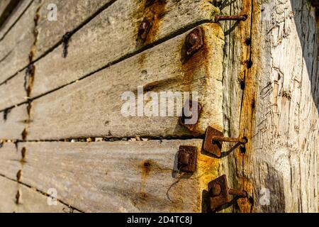 Tavole di legno pesanti fissate da bulloni arrugginiti su un mare groyne Foto Stock
