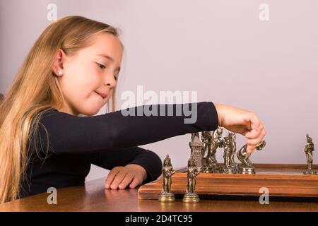 Profilo ritratto di giovane ragazza che gioca a scacchi muovendo una pedina sulla tavola. Messa a fuoco sulla mano isolata su sfondo bianco Foto Stock