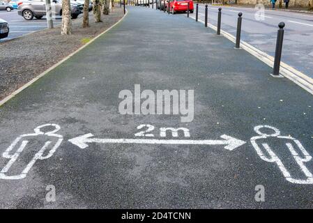 Cartello di avvertimento di distanziamento sociale per mantenere la distanza di due metri dipinto su marciapiede o marciapiede per le strade di Killarney, Contea di Kerry, Irlanda Foto Stock