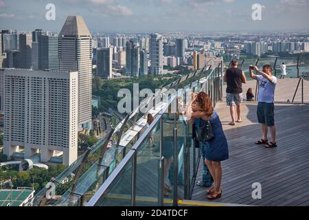 I turisti che amano e fotografano la vista dello skyline di Singapore dallo SkyPark in cima al Marina Bay Sands Hotel a Marina Bay, Singapore Foto Stock