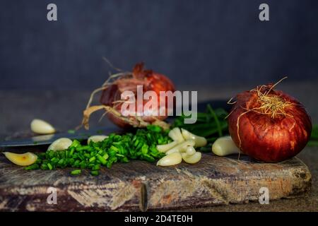 Spicchio di cipolla tagliata a fette, aglio e cipolle su un tagliere di legno Foto Stock