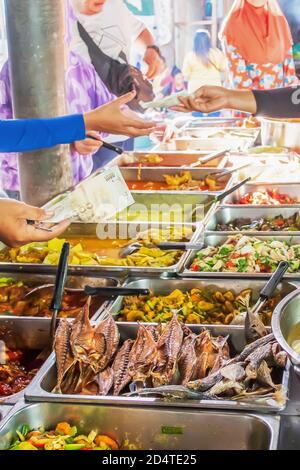 Scena mattutina al chiosco di piatti casalinghi Halal venduto nel mercato giornaliero, Narathiwat, Thailandia meridionale. Focus sulla banconota. Foto Stock