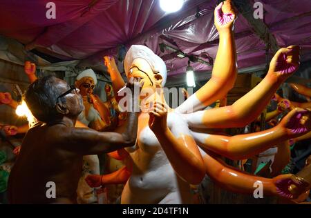 Un artista ottogenario dipinge un idolo della dea indù Durga in preparazione al prossimo festival religioso indù Durga Puja a Kolkata. Foto Stock