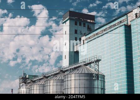 Silos agricoli. Deposito ed essiccazione di grani, grano, mais, soia, girasole. Esterno dell'edificio industriale. Grandi contenitori in argento metallizzato primo piano. Foto Stock