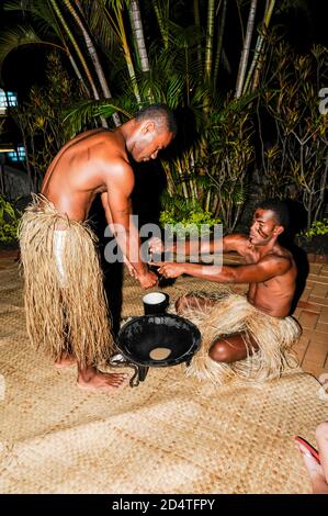 Due fijiani si accovacciano ad uno spettacolo turistico per servire la bevanda nazionale delle Fiji, Yaqona, chiamata anche Kava nelle Fiji nel Pacifico del Sud. Yaqona o Kava Foto Stock