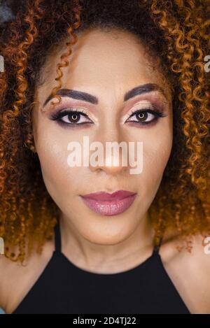 Ritratto di una bella donna afroamericana con un colore rosso arricciato capelli e trucco Foto Stock