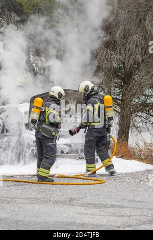 I vigili del fuoco spengono un incendio su un'auto in fiamme in una zona forestale, Mijas, Spagna. Foto Stock