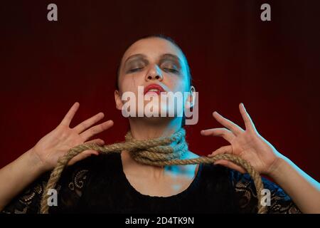 Grave donna con fune sul suo collo su sfondo rosso Foto Stock