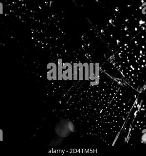 Sfondo di vetro rotto in nero. Sfondo nero minimalista con crepe sul vetro con gocce d'acqua. Foto Stock