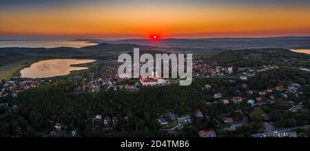 Tihany, Ungheria - veduta aerea panoramica del Monastero Benedettino di Tihany (Abbazia di Tihany, Tihanyi Apatsag) con lago interno e bellissimo cielo dorato a. Foto Stock