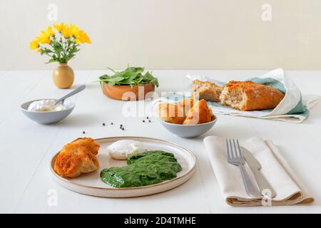 Spinaci freschi e cremosi fatti in casa e uova in camicia con pane tostato. Delizioso brunch o pranzo sano. Vista ad angolo basso. Foto Stock