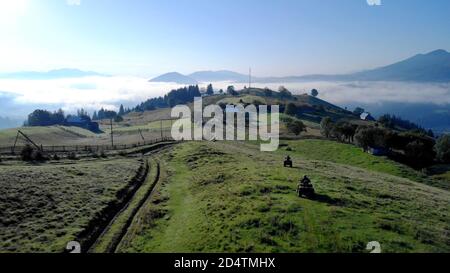 Le quad si guidano sulle verdi colline verso il villaggio. Foto Stock