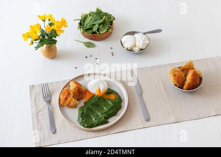 Spinaci freschi e cremosi fatti in casa e uova in camicia con pane tostato. Delizioso brunch o pranzo sano. Foto Stock