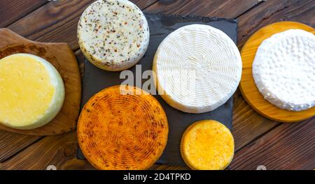 Teste di formaggio con formaggi di vario genere. Assortimento di diversi tipi di formaggio su sfondo ligneo. Latticini freschi, alimenti biologici sani. Delizioso apetizzatore. Mercato di campagna. Formaggio fatto in casa. Foto Stock