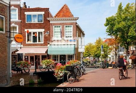Vista sul centro storico di Gouda. Zeugstraat e Lange Tienderweg con canale, ponte, negozi e case tradizionali in un pomeriggio soleggiato. Hollan del sud Foto Stock
