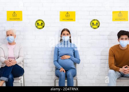 Persone in attesa di essere vaccinate contro Coronavirus seduto in ospedale Foto Stock