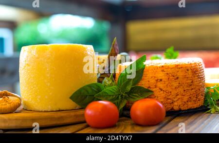 Teste di formaggio con formaggi di vario genere. Assortimento di diversi tipi di formaggio su sfondo ligneo. Latticini freschi, verdure varie, cibo biologico sano. Delizioso apetizzatore. Mercato di campagna. Formaggio fatto in casa. Foto Stock