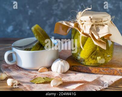 Vasetti fatti in casa di cetrioli sottaceto con aglio su un rustico sfondo di legno. Prodotto decapato e in scatola. Cetrioli fermentati su sfondo scuro. Foto Stock