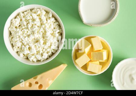 I prodotti più comuni del latte sono il burro, il formaggio, il latte, la panna acida, il formaggio di cottage su una carta verde di fondo piatto. Cibo naturale e biologico. Alimenti Foto Stock