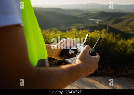 Closeup di mani di lavoratore maschile che tiene un telecomando drone controllo in campagna Foto Stock