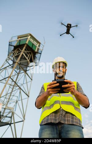 Drone operatore uomo pilotare un drone accanto ad una torre Foto Stock