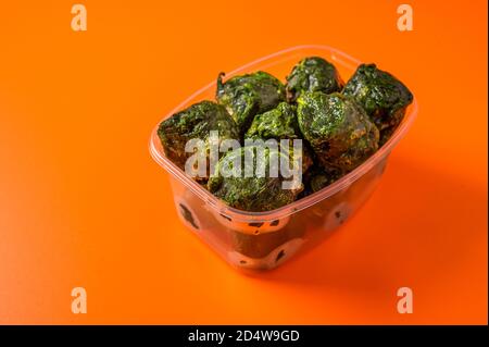 Spinaci di verdure surgelate in un vassoio di plastica su sfondo arancione, fuoco selettivo, diete concettuali e alimentazione sana con spazio di copia da vicino Foto Stock