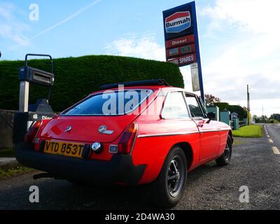 Un classico MGB GT si trova all'esterno di una stazione di rifornimento abbandonata Foto Stock