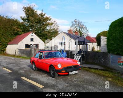 Un classico MGB GT si trova all'esterno di una stazione di rifornimento abbandonata Foto Stock