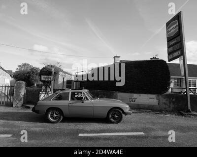 Un classico MGB GT si trova all'esterno di una stazione di rifornimento abbandonata Foto Stock