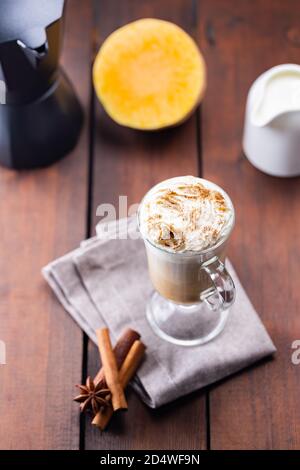 Latte di zucca, caraffa di latte e un pezzo di zucca. Latte di zucca con panna montata e spezie su tavole di legno. Bevanda calda autunnale al caffè su un pisolino di lino Foto Stock