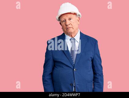 Uomo anziano bello con capelli grigi che indossa abiti e architetto hardhat scettico e nervoso, disapprovando l'espressione sul viso con le braccia incrociate. pe negativo Foto Stock