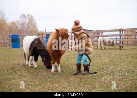 Ragazza che cammina con carino pony poco Foto Stock