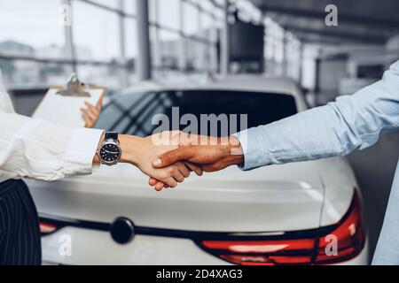 Donna venditore di auto e uomo acquirente di auto handshaking in auto salone Foto Stock