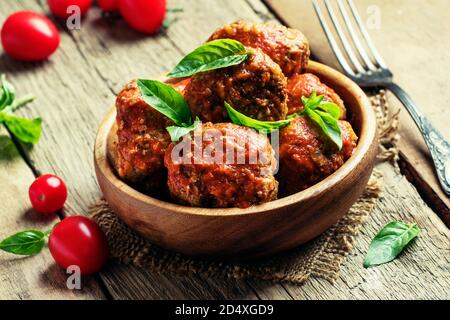 Polpette di maiale e manzo con salsa piccante di pomodoro in ciotola, fondo ligneo vintage, fuoco selettivo Foto Stock