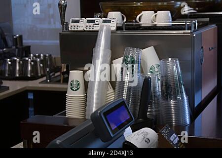 San Pietroburgo, Russia - 03 OTTOBRE 2020 le tazze di carta usa e getta Starbucks si trovano vicino a una macchina per il caffè e a un registratore di cassa in un bar Starbucks Foto Stock