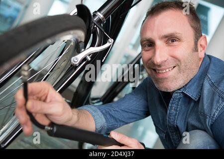 l'operatore gonfia la ruota di bicicletta utilizzando una pompa Foto Stock