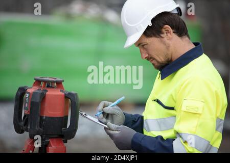 geometro uomo prende misure sul cantiere Foto Stock