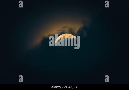 Luna di notte parzialmente coperta dalla nuvola. Luna piena di nuvole drammatiche nel cielo notturno. Foto Stock
