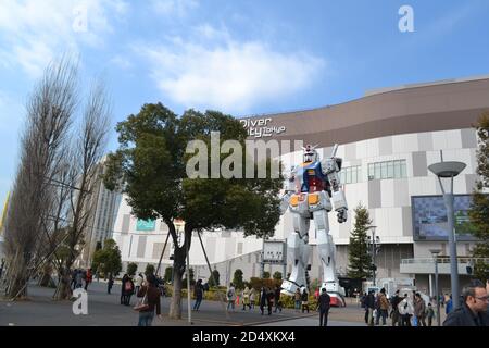 Tokyo, Japan-2/26/16: Folle di persone si riuniscono intorno alla statua a grandezza naturale dell'RX-78-2 Gundam, noto dall'anime Gundam. Foto Stock