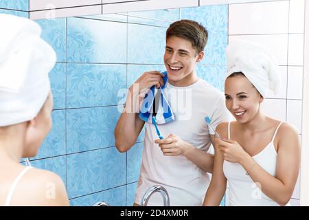 Una giovane coppia sta spazzolando i denti. La coppia si stolge in bagno. Fotografia lifestyle Foto Stock