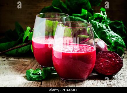 Frullato di barbabietole in un grande bicchiere, barbabietole fresche con top, vecchio sfondo di legno, fuoco selettivo Foto Stock