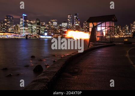 Vancouver 9 o'Clock Gun che scatta al buio con il paesaggio urbano sullo sfondo. Foto Stock