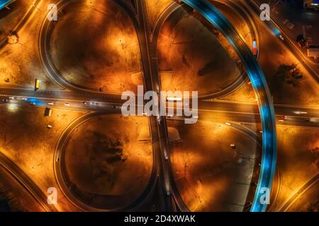 Grande rotonda o incrocio di trasporto stradale di notte con traffico automobilistico, vista dall'alto. Foto Stock