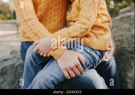 dolce abbraccio di genitore e bambino vestito lo stesso. caldo autunno maglia abbigliamento: giallino maglione e jeans blu. autunno passeggiate in aria fresca Foto Stock